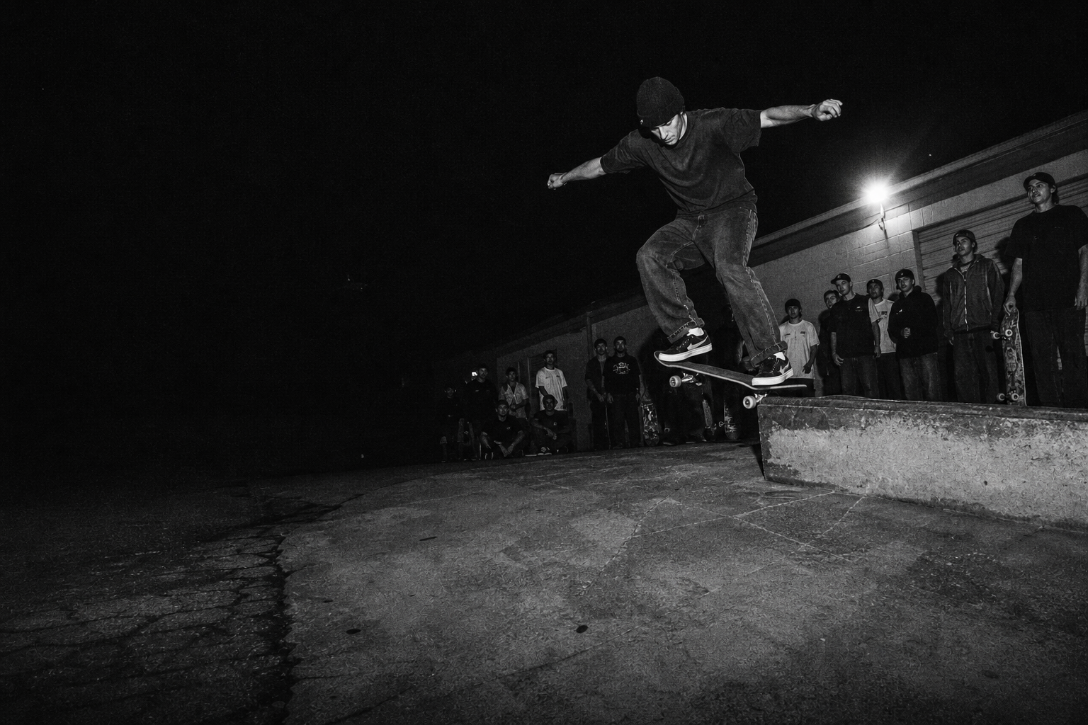 Black and white skater riding a curb at night